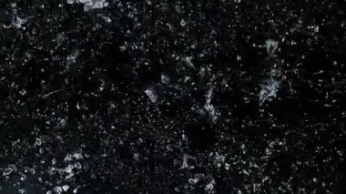 Siyah arka planda su sıçraması, süper yavaş çekim. Yüksek hızlı sinema kamerasıyla çekilmiş..