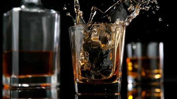 Eiswürfel fällt ins Glas mit Whisky — Stockfoto