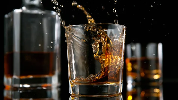 Cubo di ghiaccio che cade nel bicchiere di whisky — Foto Stock