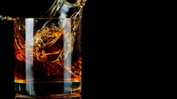 Eiswürfel fällt ins Glas mit Whisky — Stockfoto