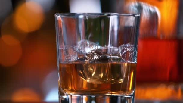 Aparat śledzi kostkę lodu wpadającą do szklanki whisky w Super Slow Motion — Wideo stockowe