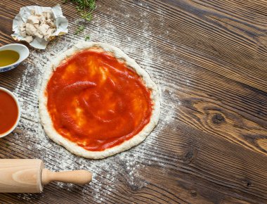 Pizza hazırlama malzemeleri ile çevrili.