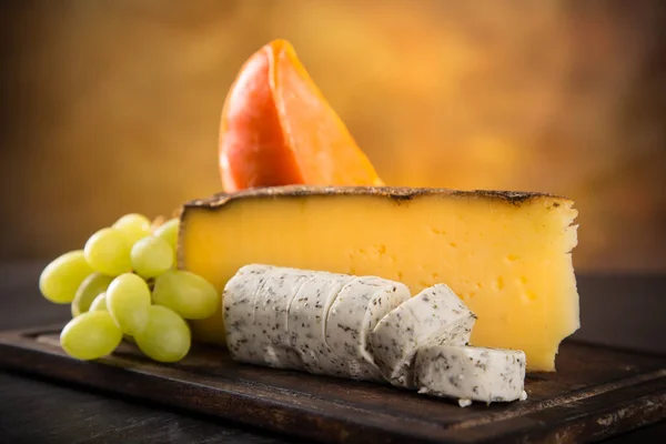나무 배경 위에 여러 종류의 치즈를 놓는 모습. — 스톡 사진