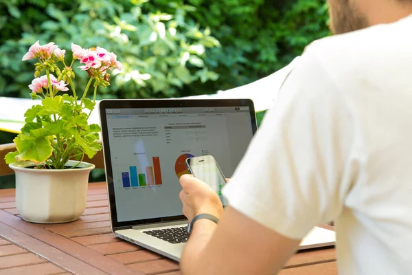 Az ember laptopon dolgozik a kertben és kávét iszik.. — Stock Fotó
