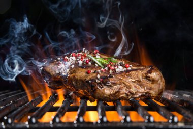 Lezzetli biftek, dökme demir ızgara ve ateş alevi..