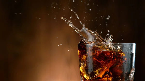 Cola häller i ett glas med isbitar — Stockfoto