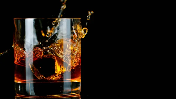 Eiswürfel fällt ins Glas mit Whisky — Stockfoto