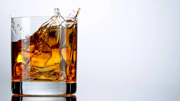 Eiswürfel fällt ins Glas mit Whisky — Stockfoto