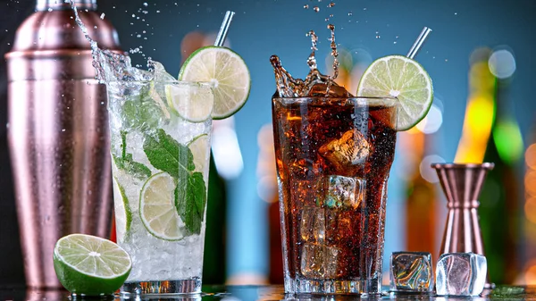 Mojito with Cuba libre cocktails splashing in a bar. — Stock Photo, Image