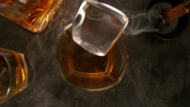 Cámara sigue hielo caído cayendo en el vaso de Whisky en Super cámara lenta. — Vídeos de Stock