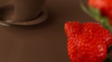Erimiş çikolatanın içine sıçrayan taze çileklerin süper yavaş çekimleri..