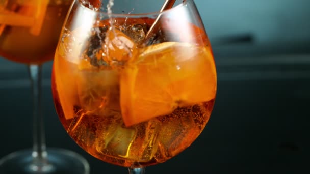 Cubo di ghiaccio che cade in vetro di cocktail arancione. — Video Stock