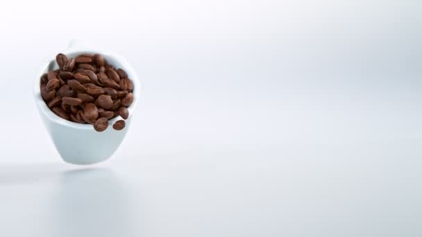 Taza de café en cámara súper lenta con granos de café tostados — Vídeos de Stock