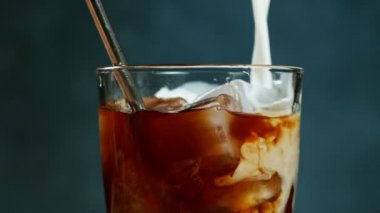 Ağır çekimde soğuk demlenmiş buzlu kahveyi bardağa dolduruyor.