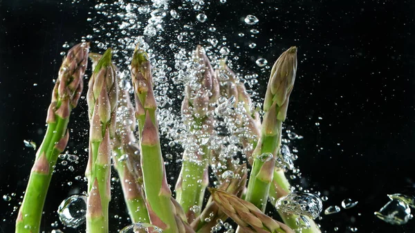 Asparagus in water with splashes — Stock Photo, Image