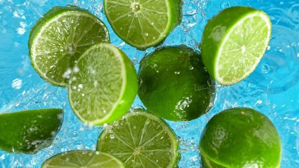 Limas frescas que caen al agua con salpicaduras —  Fotos de Stock