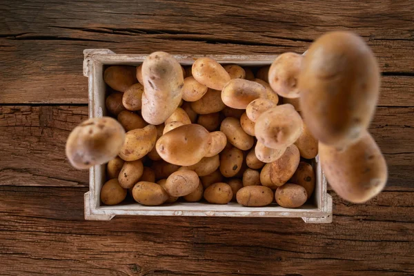 Čerstvě sklizené brambory padající do dřevěné krabice. — Stock fotografie