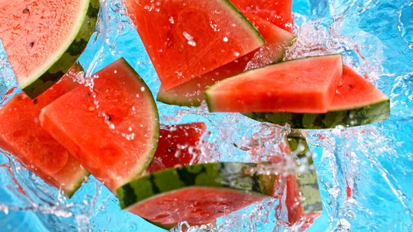 Trozos de sandía fresca cayendo en agua con salpicaduras —  Fotos de Stock