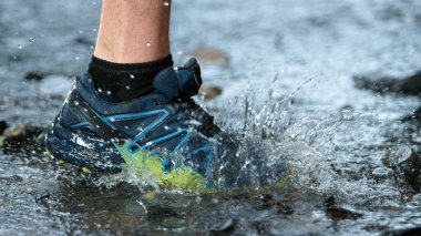 Spor ayakkabılı bir koşucunun hareketsiz hareketleri orman deresine sıçrıyor..