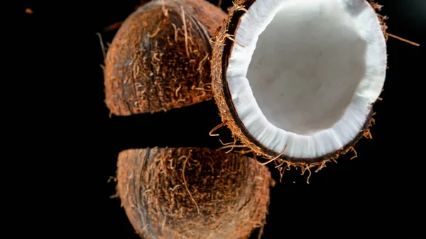 Gebarsten kokosnoten vallen neer op zwarte achtergrond. — Stockfoto