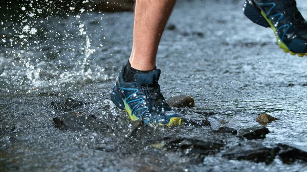 Gel mouvement des jambes d'un coureur en baskets éclaboussant dans le ruisseau forestier. — Photo