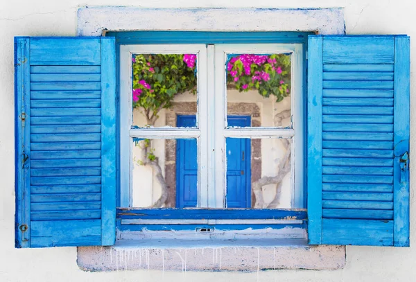 Иконическое голубое деревянное окно на белой каменной стене типичного греческого дома — стоковое фото