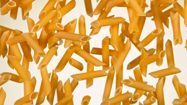 Frys rörelse flyga okokt italiensk pasta penne på vit bakgrund. — Stockfoto