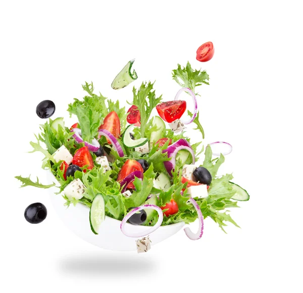 Fresh salad with flying vegetables ingredients Royalty Free Stock Photos