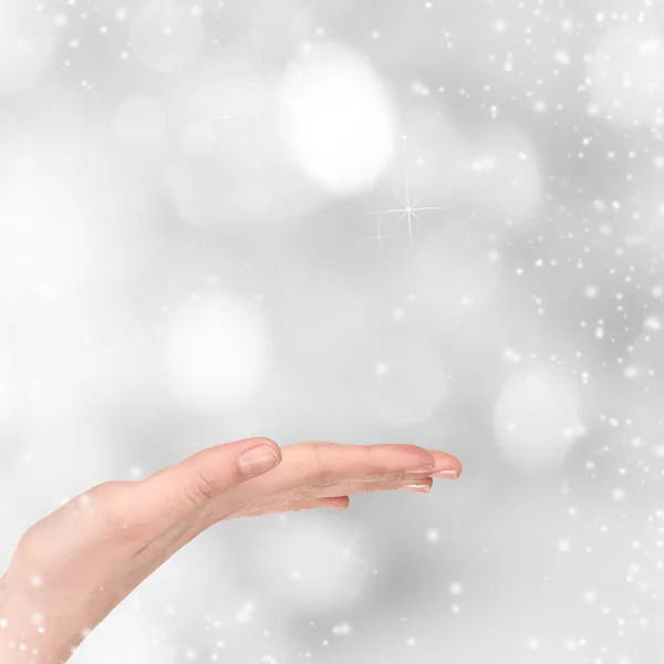 Frau Hand auf weihnachtlichem Hintergrund — Stockfoto