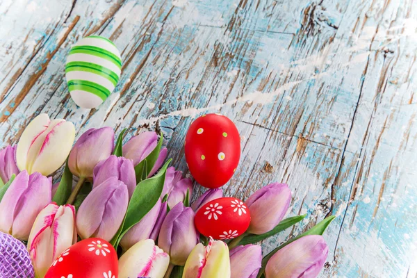 Tulips and easter eggs on wooden background — Stock Photo, Image