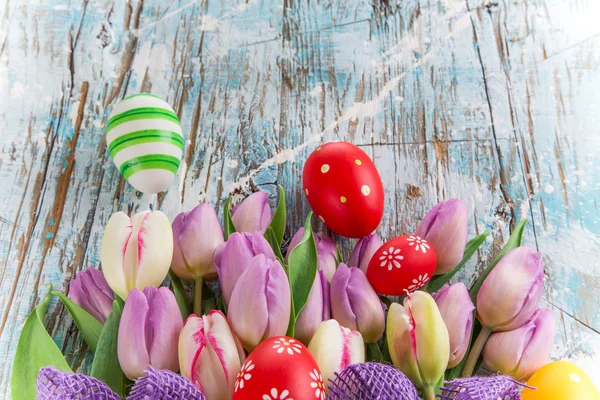 Tulips and easter eggs on wooden background — Stock Photo, Image