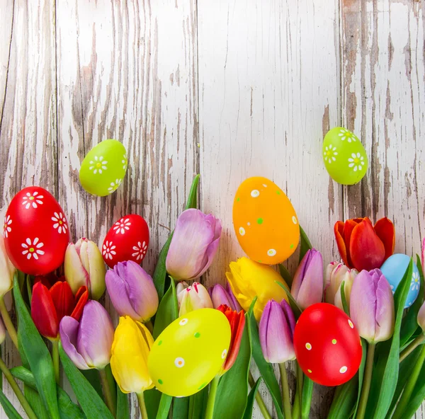 Tulipány a kraslic na dřevěné pozadí — Stock fotografie