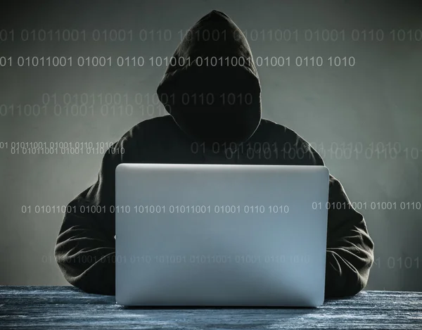 Un hacker con cappuccio e laptop — Foto Stock