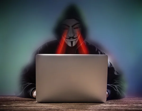 Um hacker com um capuz com laptop — Fotografia de Stock
