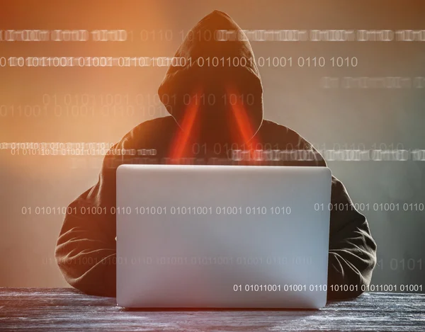 En hacker med en huva med laptop — Stockfoto