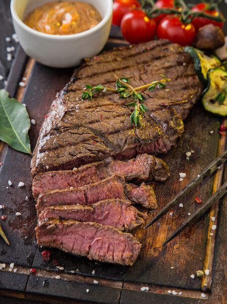 Стейк из говядины на черном каменном столе
