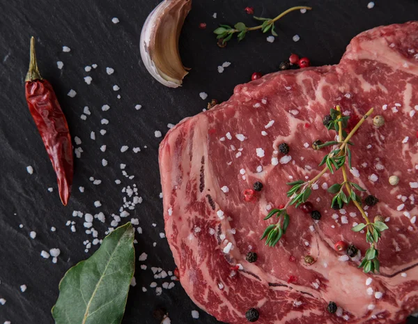 Bistecca di manzo cruda sul tavolo nero — Foto Stock