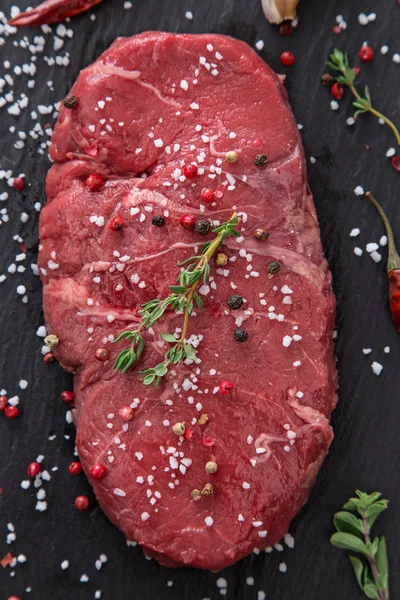 Bife de carne crua em mesa preta — Fotografia de Stock