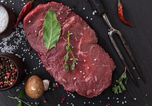 Bife de carne crua em mesa preta — Fotografia de Stock