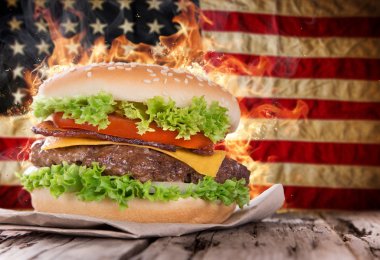 Yangın alevler ve Amerikan bayrağı ile lezzetli hamburger