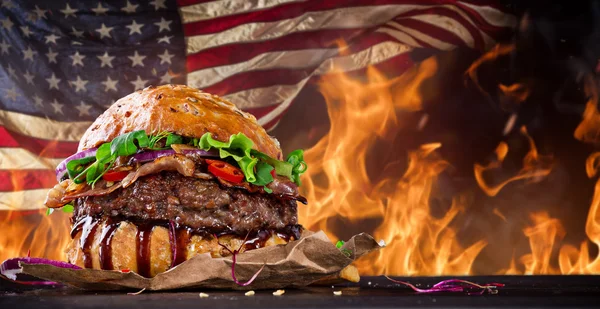 Leckerer Hamburger mit Feuerflammen und amerikanischer Flagge — Stockfoto