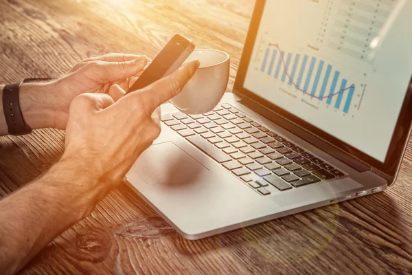 Mann arbeitet mit Smartphone und Notebook. — Stockfoto