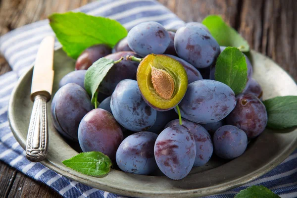 Fresh plums on old wooden table — Stock Photo, Image