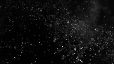 Siyah bir zeminde havada parçacıklar ve toz var. 1000 fps 'lik yüksek hızlı bir sinema kamerasında çekildi.