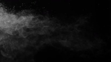 Siyah bir zeminde havada parçacıklar ve toz var. 1000 fps 'lik yüksek hızlı bir sinema kamerasında çekildi.