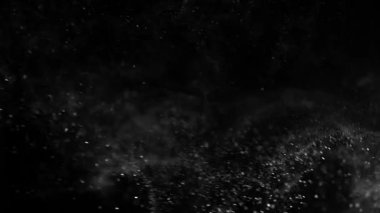 Siyah bir zeminde havada parçacıklar ve toz var. 1000 fps 'lik yüksek hızlı bir sinema kamerasında çekildi.