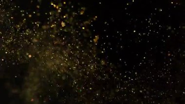 Siyah zemin üzerinde izole edilmiş küçük altın parçacıklar uçuşuyor. Yüksek hızlı kamera, 1000 fps.