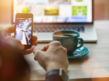 Man working on notebook, with a fresh cup of coffee and cell phone.