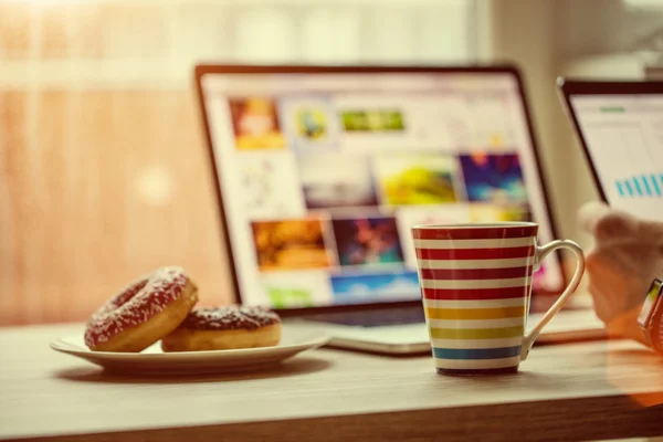 Hombre trabajando en el cuaderno, con una taza de café fresco . — Foto de Stock