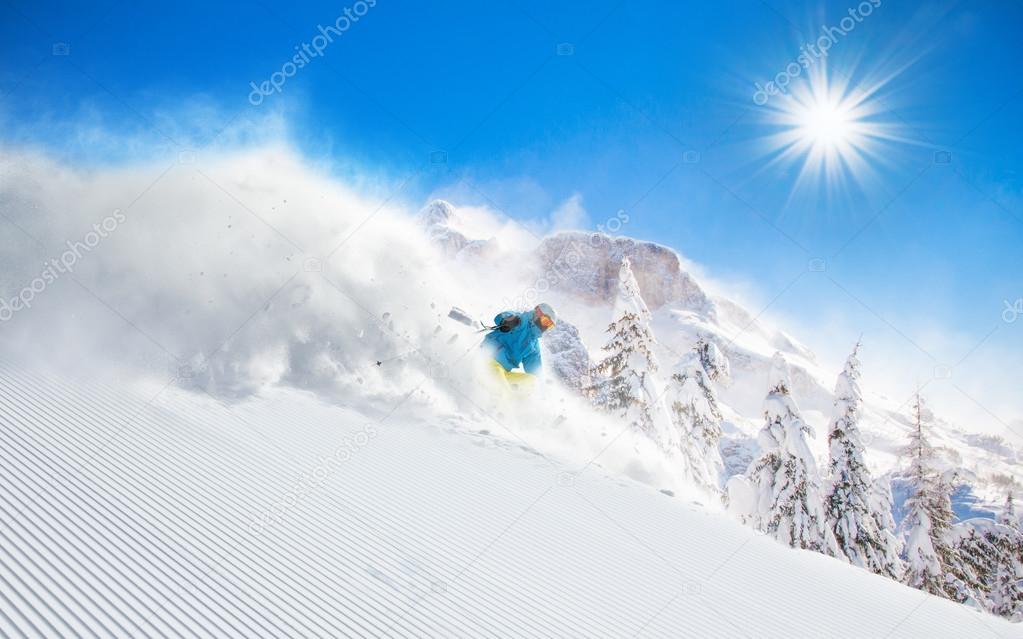 Skier skiing downhill in high mountains